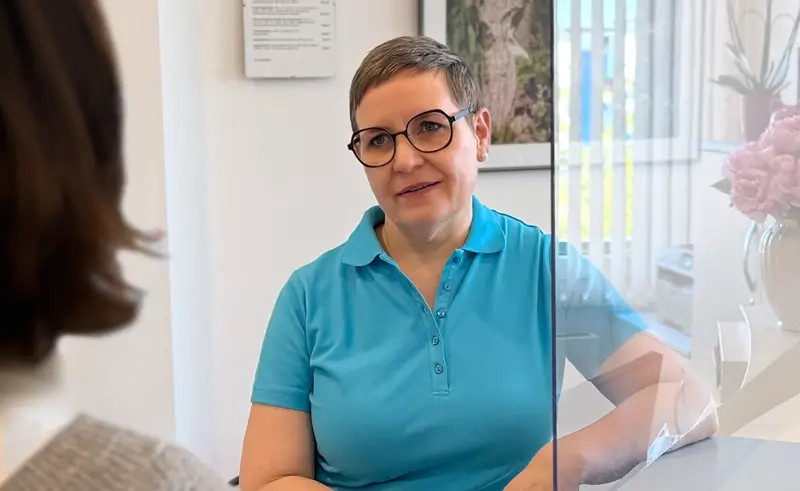 Die HNO-Ärztin Maren Festner im persönlichen und beratenden Gespräch mit einer Patientin am Empfangstresen ihrer Praxis.