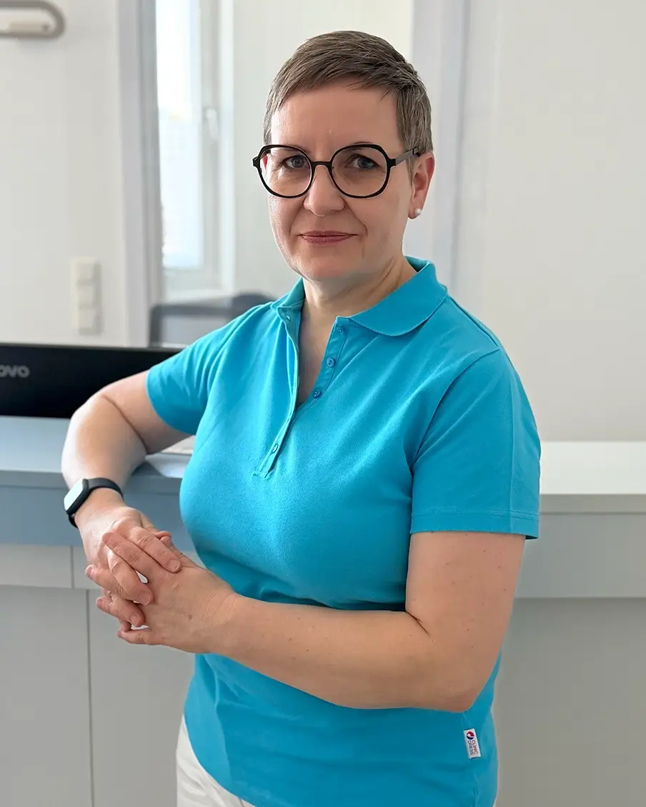Portrait der HNO-Fachärztin Maren Festner im Hochformat, freundlich lächelnd am Empfangstresen ihrer modernen Praxis.