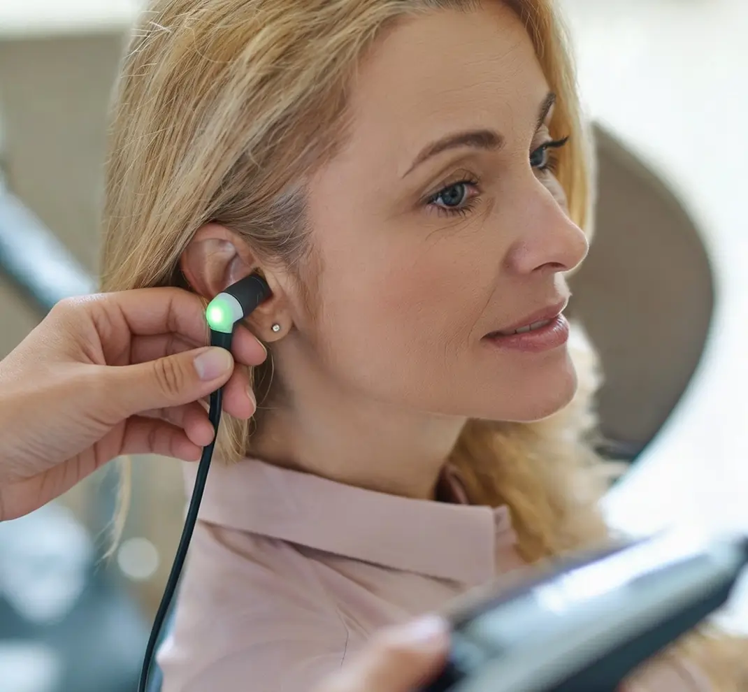 Untersuchung des Gehörgangs: Eine Patientin erhält eine headphone- oder sondenbasierte HNO-Messung am Ohr.