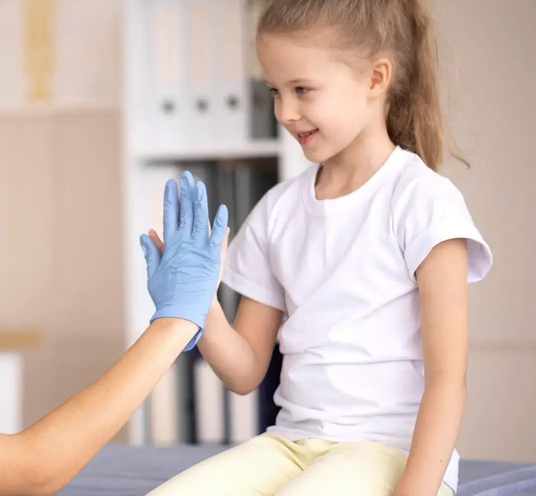 Ein junges Mädchen gibt einer HNO-Ärztin mit medizinischem Einweghandschuh ein High-Five.
