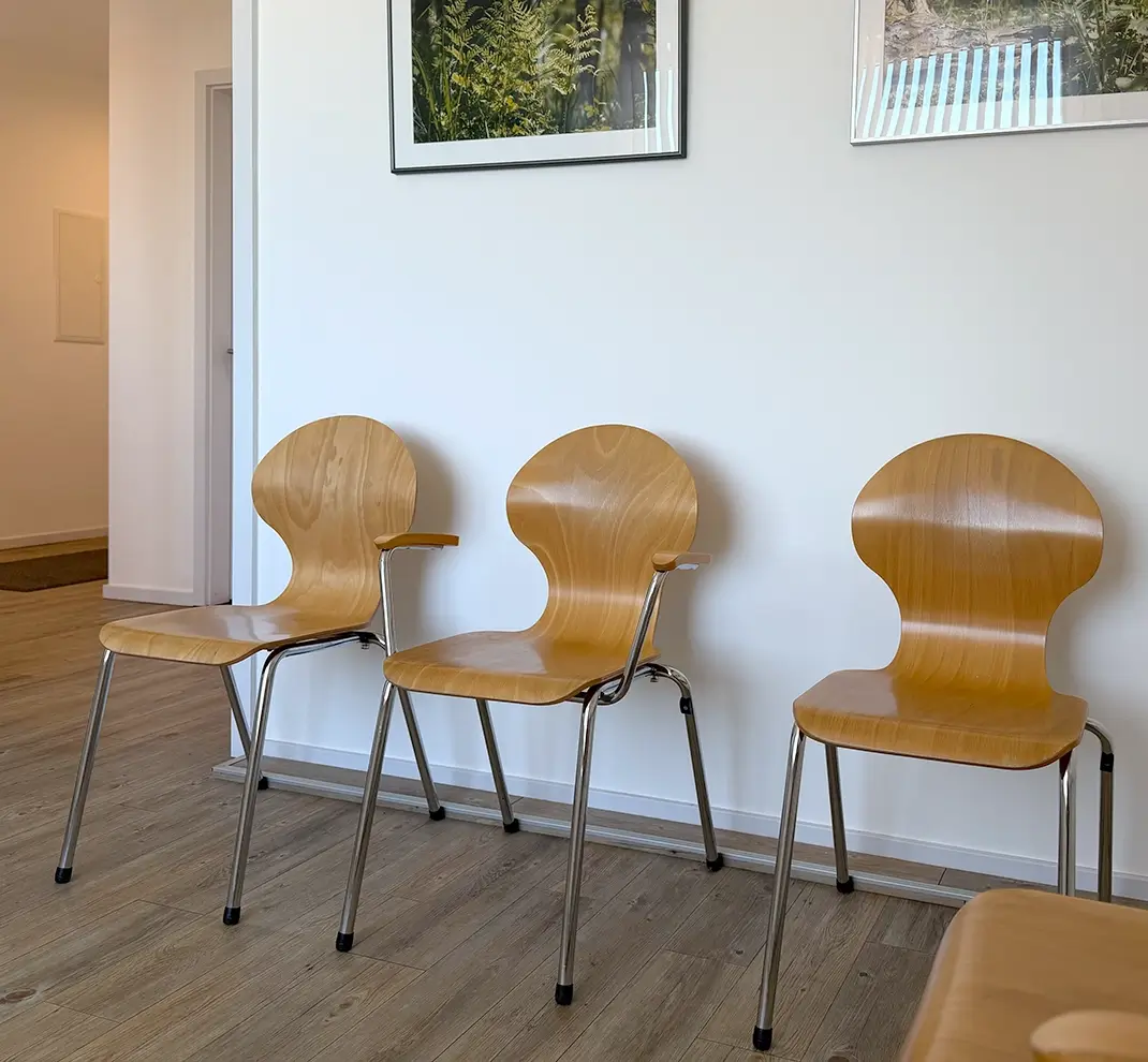 Heller und moderner Wartebereich mit ergonomischen Holzstühlen und beruhigenden Naturbildern an der Wand in der HNO-Praxis Maren Festner.